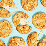Bueno New York Cookie with white chocolate hazelnut filling, chopped nuts, and crispy feuilletine on blue background.